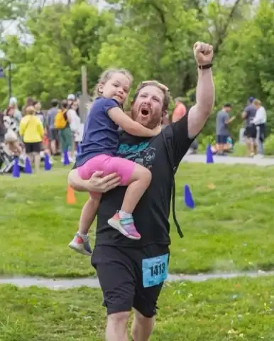 Chef Zak celebrating at a race finish line with his daughter Fallon in his arms